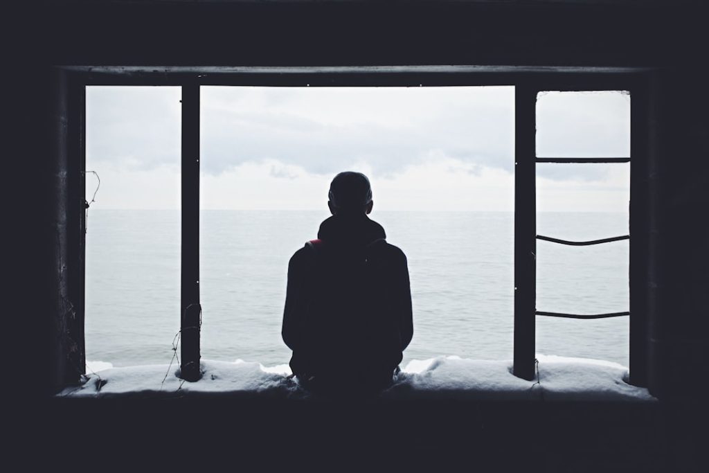Person looking out through a window alone