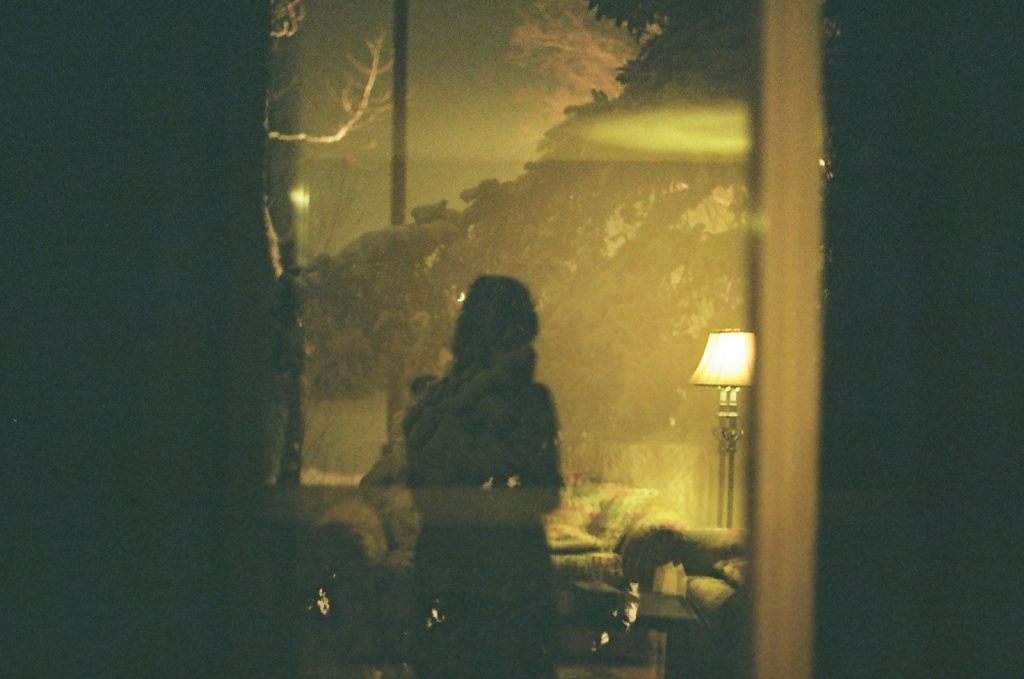 A person standing by a window at night