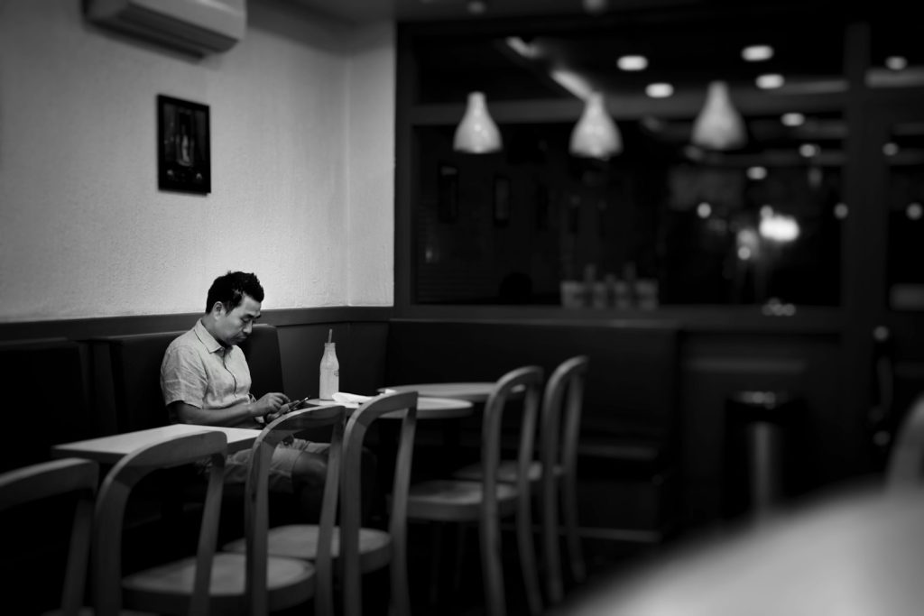 Person sitting alone in a cafe with a phone