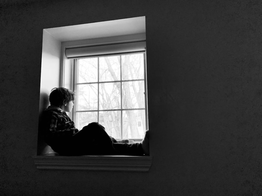 Grayscale photo of two people sitting beside a window by Amanda Gueraldi on Unsplash